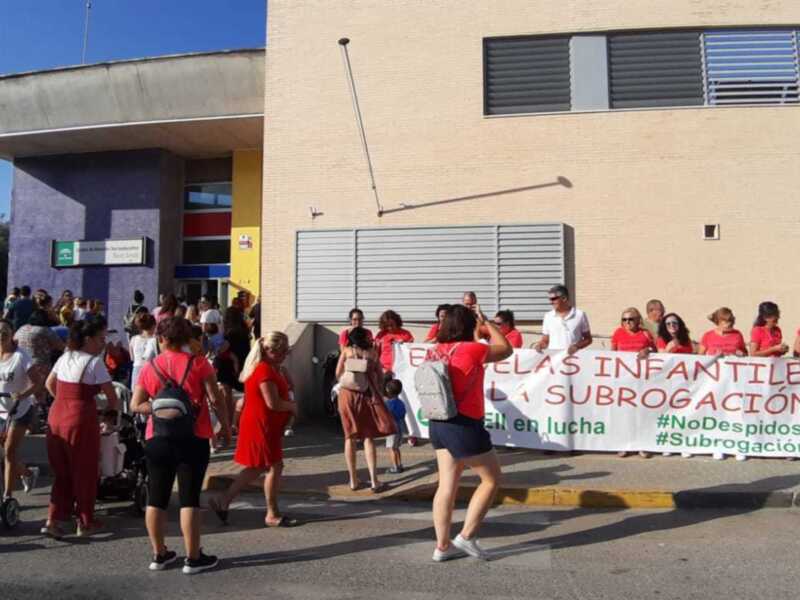 Manifestación de trabajadores de la educación frente a un centro escolar, con pancarta que dice 'EN DEFENSA DE LAS INFANTIL EN LUCHA' y '#NoDespidos'.