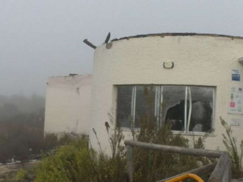 Casa circular con paredes blancas y ventanas, rodeada de vegetación y niebla.