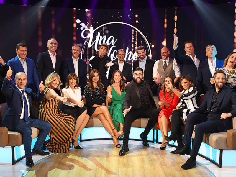 Grupo de personas en un escenario televisivo celebrando juntos.