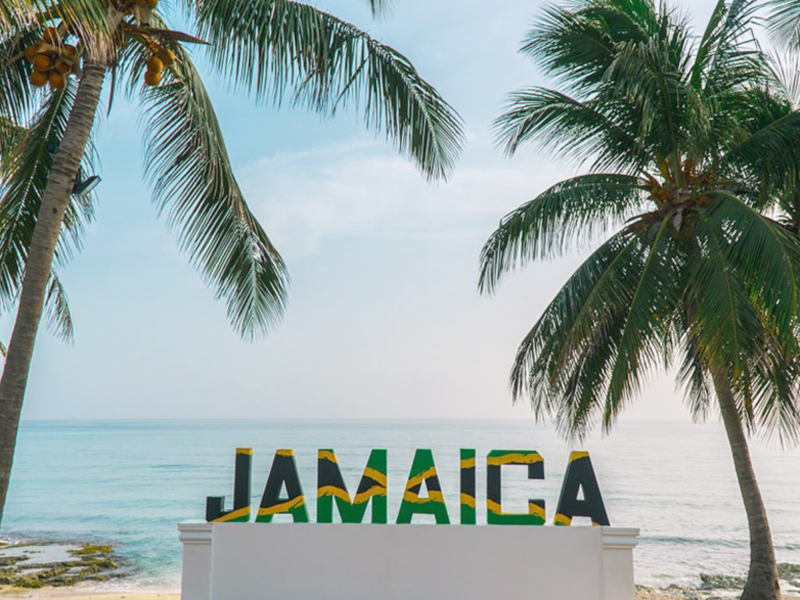 Jamaica sign with palm trees and ocean in the background.