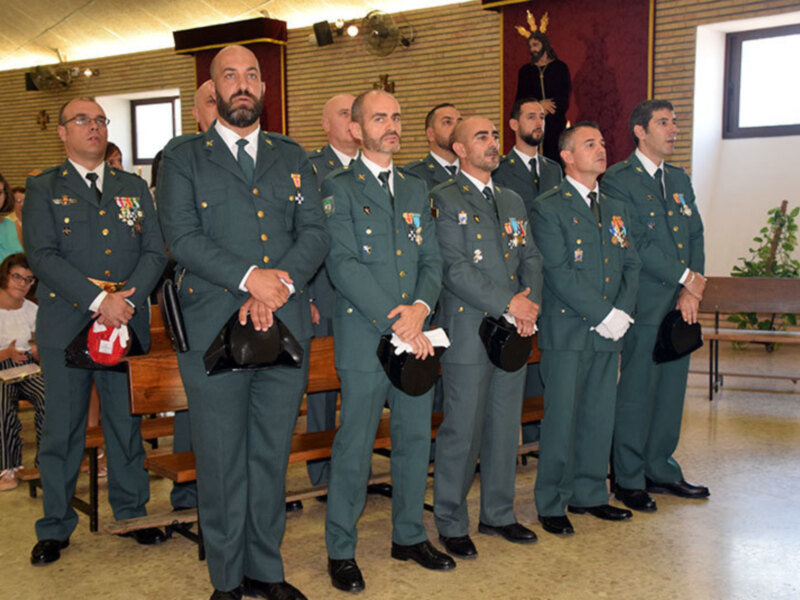 Uniformados en una ceremonia militar en un salón con bancos y decoración religiosa.