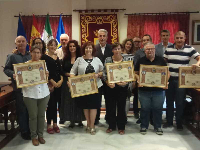 Celebración de premios en un evento oficial con participantes sosteniendo certificados.