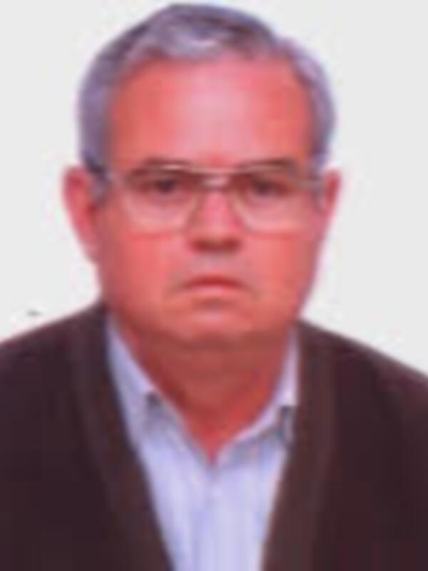Un hombre con gafas y una camisa blanca, posando para una foto.