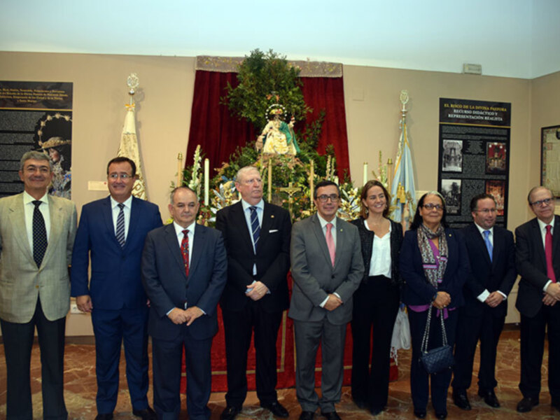 Celebración de la Virgen de la Divina Pastora en un evento oficial con autoridades y representantes en un salón decorado con flores y banderas.