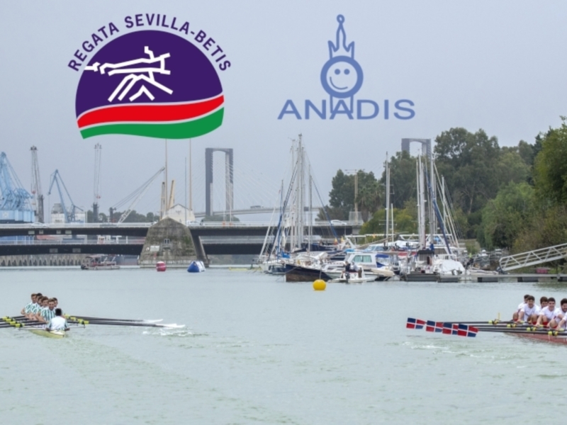 Regata Sevilla-Betis en el río Guadalquivir, con barcos y equipos de remo en el agua. Logotipos de Regata Sevilla-Betis y ANADIS en la imagen.