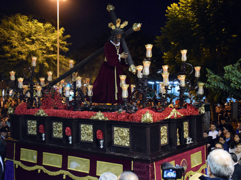 Carnaval de las Palmas de Gran Canaria, España. Estatuas de San Juan Evangelista y San Juan Bautista en procesión nocturna. Estatuas con velas y flores rojas, público en el fondo.