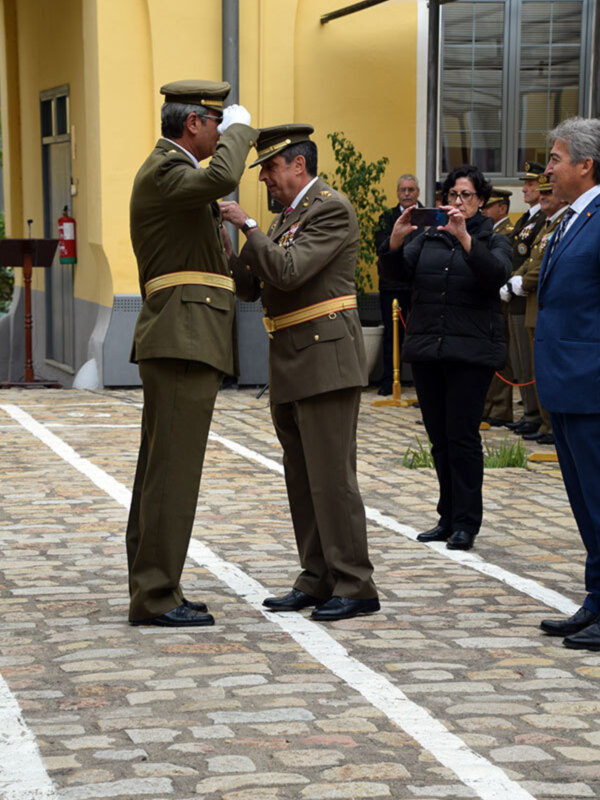Oficial militar condecorando a otro oficial en una ceremonia formal al aire libre.