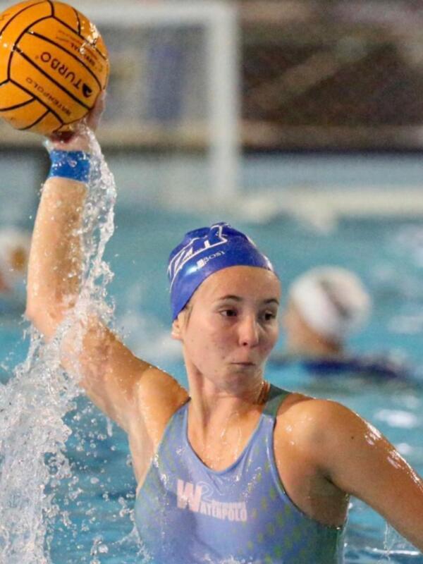 Jugadora de waterpolo en acción, lanzando el balón en una piscina.