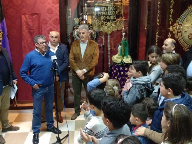 Presentación en un evento formal con niños y adultos en un salón decorado con elementos históricos.