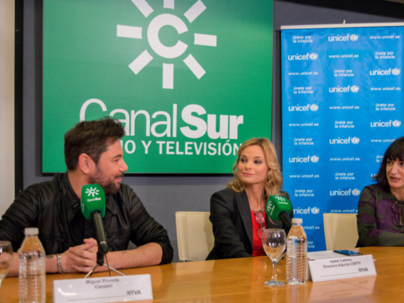 Panel de discusión en Canal Sur con logos de UNICEF en el fondo, tres personas sentadas en una mesa con micrófonos y tarjetas de nombre.