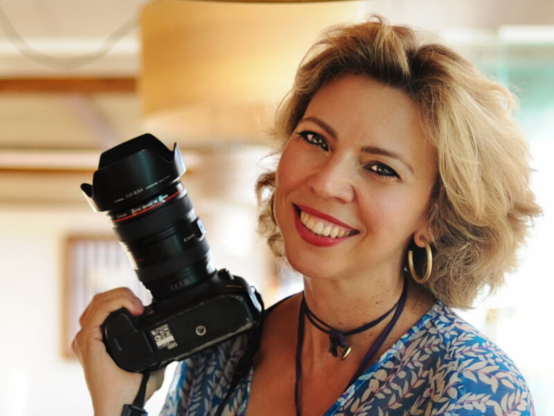 Retrato de una mujer sonriente sosteniendo una cámara de fotografía