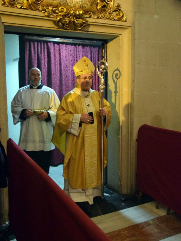 Imaginación: Un sacerdote en vestimenta religiosa, posiblemente en un evento religioso, con un fondo que sugiere un entorno de iglesia o templo.