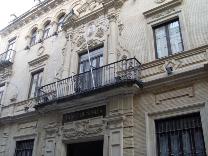 Fachada del Ateneo de Sevilla, un edificio con detalles arquitectónicos clásicos y balcones forjados.
