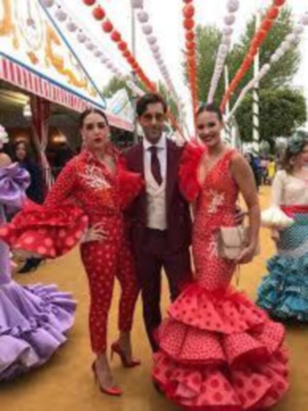 Danzantes en trajes flamencos en un evento festivo con decoración de carnaval.
