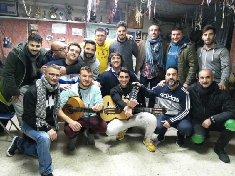 Grupo de amigos disfrutando de una tarde de música y risas en un local decorado con banderines y trofeos.
