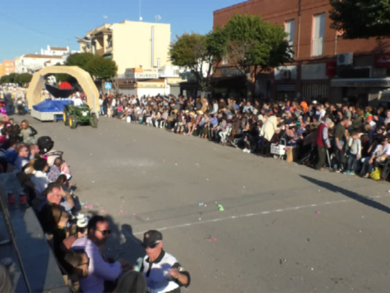 Carnaval en la calle con multitud de espectadores y carrozas en desfile.