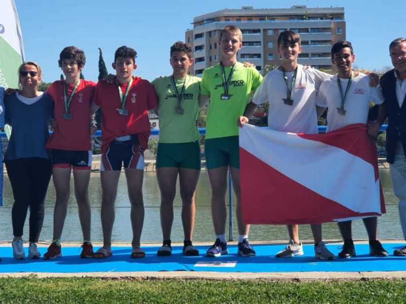 Equipo deportivo con medallas y bandera, posando en el podio junto a autoridades.