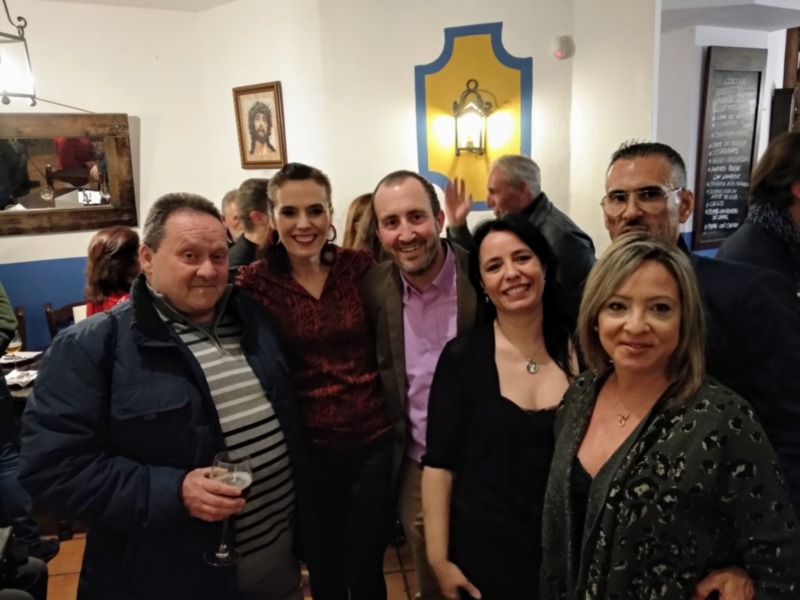 Una familia feliz en una reunión familiar, con un retrato y un escudo en el fondo.