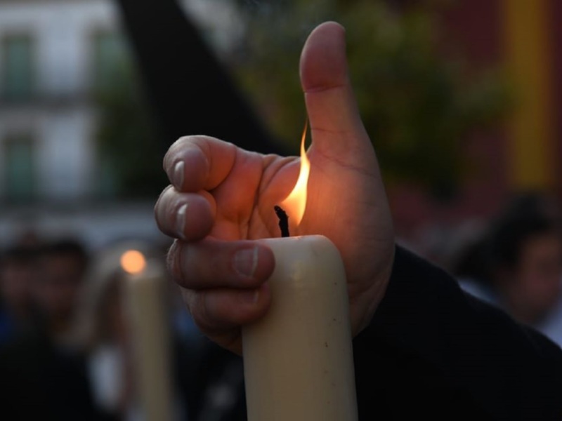 Mano sosteniendo una vela encendida en una celebración o ceremonia.