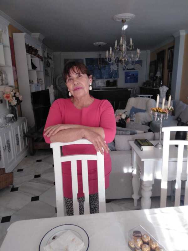 Retrato de una mujer sentada en una silla en un elegante salón con decoración clásica y un ambiente acogedor.