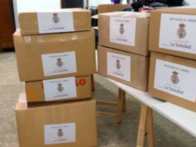 Cajas de donaciones etiquetadas "La Soledad" en una mesa.