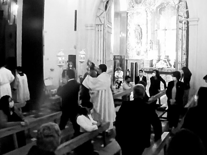 Procesión religiosa en una iglesia, con sacerdotes y fieles en un ambiente solemne.