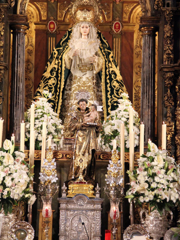 Altar con estatuas religiosas y decoración floral, representando una escena de culto católico.