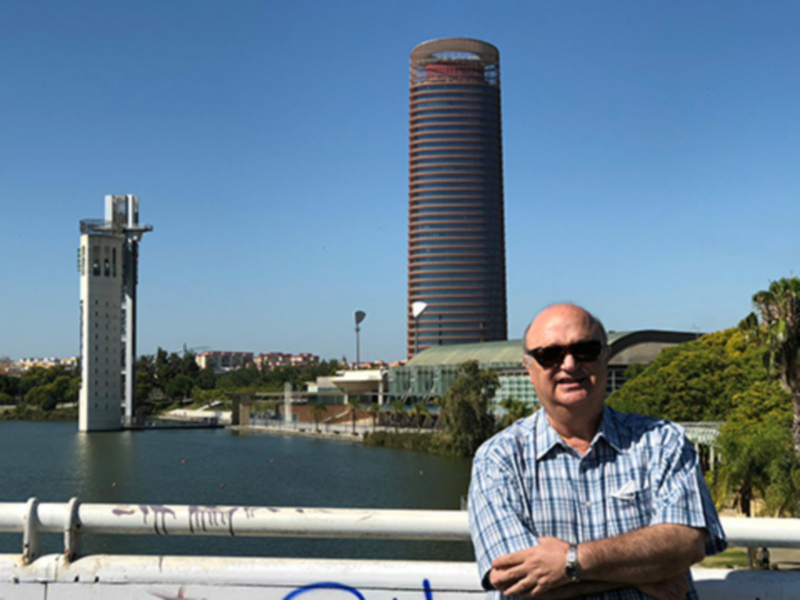 Hombre posando frente a la Torre Sevilla y el río Guadalquivir en Sevilla, España.