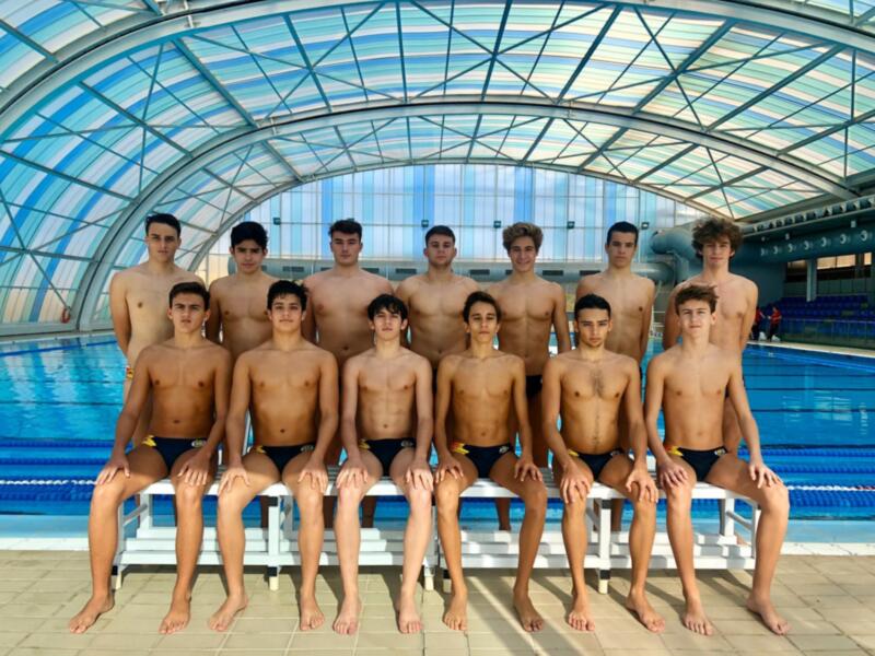 Equipo de natación juvenil posando en la piscina cubierta.