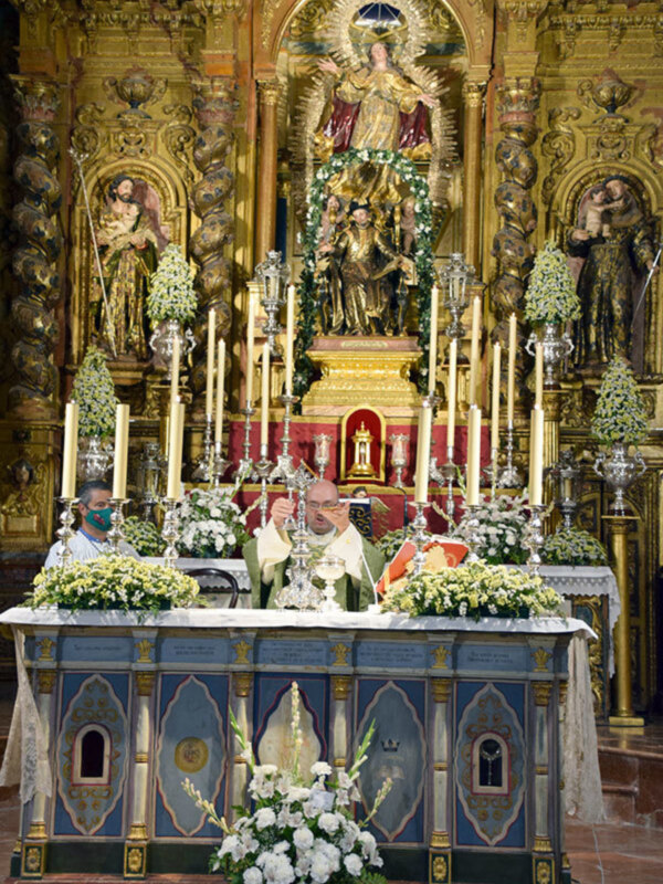 Interior de una iglesia con altares ornamentados y figuras religiosas en un ambiente de culto.