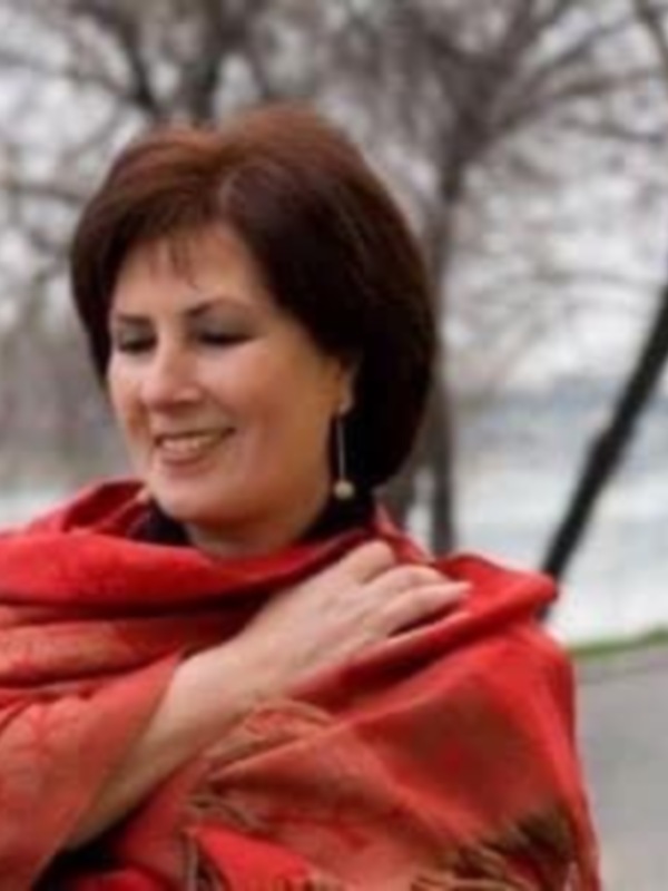 Una mujer con una bufanda roja en un día soleado, posiblemente en un parque o jardín.