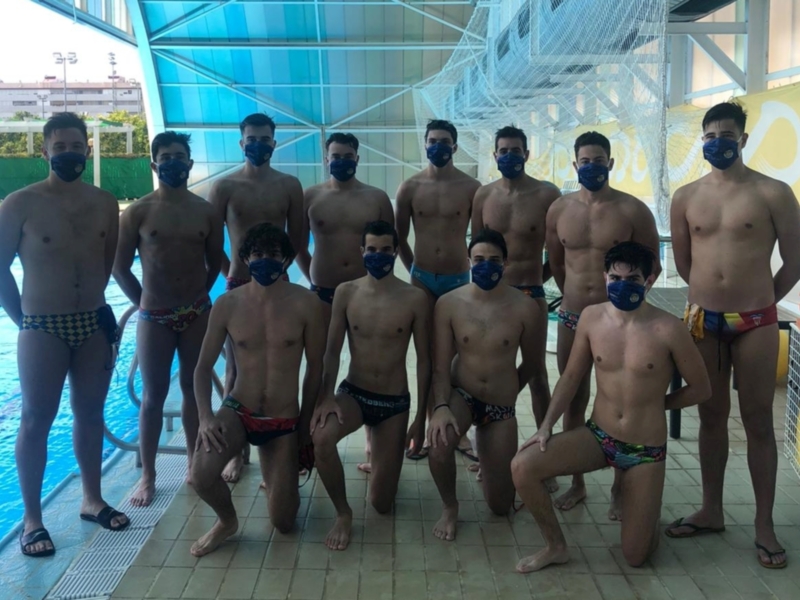 Equipo de natación posando junto a una piscina, todos con máscaras faciales y trajes de baño, mostrando un espíritu unido y preparado para competir.