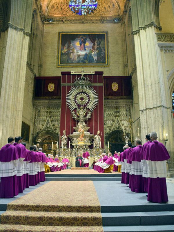 Misa en la Catedral de Sevilla, con sacerdotes en túnicas moradas y un altar ornado con estatuas y candelabros.