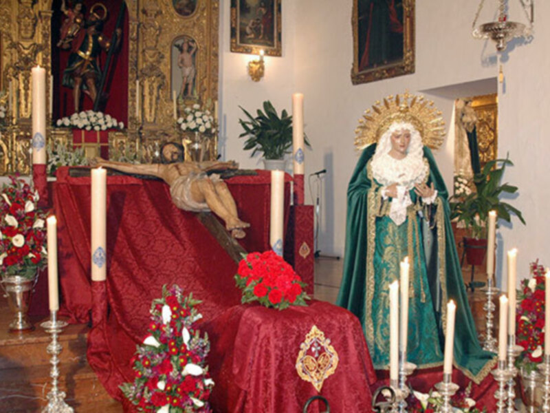 Procesión religiosa con la imagen de la Virgen y el Cristo en el altar, adornado con flores y velas.