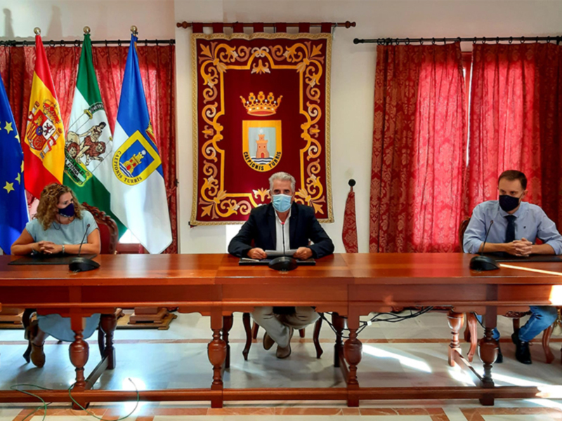 Dos personas sentadas en una mesa con banderas de España y Andalucía en el fondo.