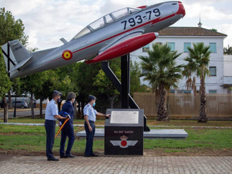 Monumento a la Aviación Militar con tres personas en uniforme frente a un avión de exhibición en un parque.