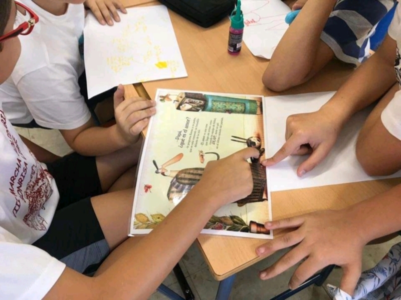 Niños en una escuela mostrando un libro de cuentos.