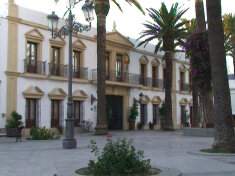 Plaza con palmeras y edificio colonial en el fondo, típico de la costa de Andalucía.