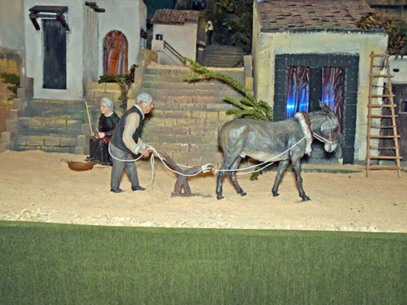 Miniatura de escena rural con personajes y un burro, representando una vida tradicional en un pueblo.