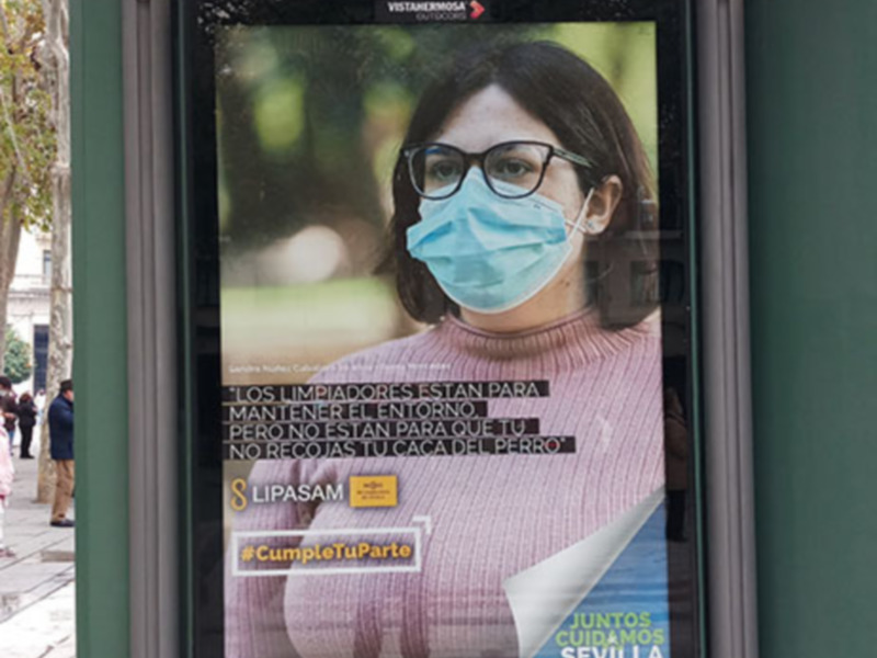 Una mujer con mascarilla en una publicidad de Sevilla, promoviendo la colaboración para combatir el coronavirus.
