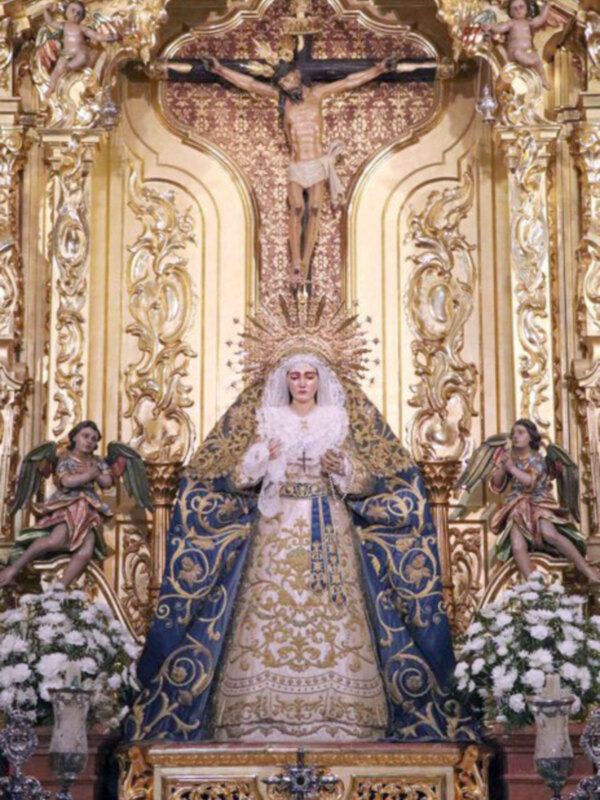 Retablo dorado con la Virgen María en trono, rodeada de ángeles y adornos florales.