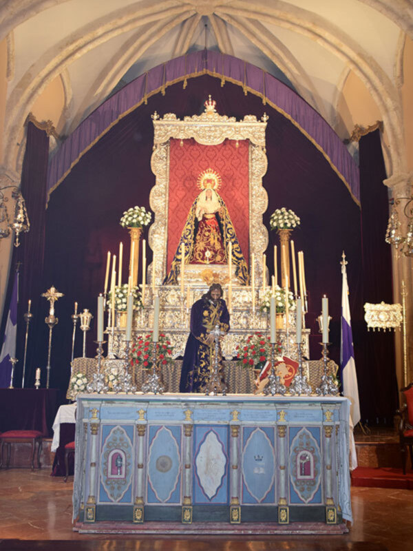 Altar con imagen de la Virgen María, adornado con velas y flores, en un ambiente con arcos y techo cúpula.