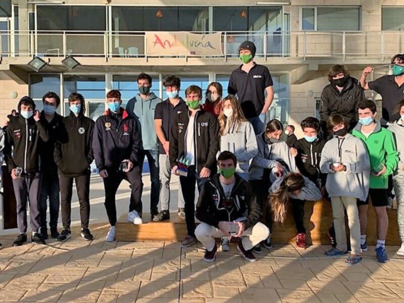 Estudiantes posando en la entrada de un edificio, con una pancarta que dice 'Andalucía' en el fondo.