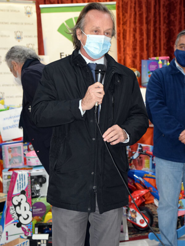 Hombre hablando en micrófono en evento de donación de juguetes.