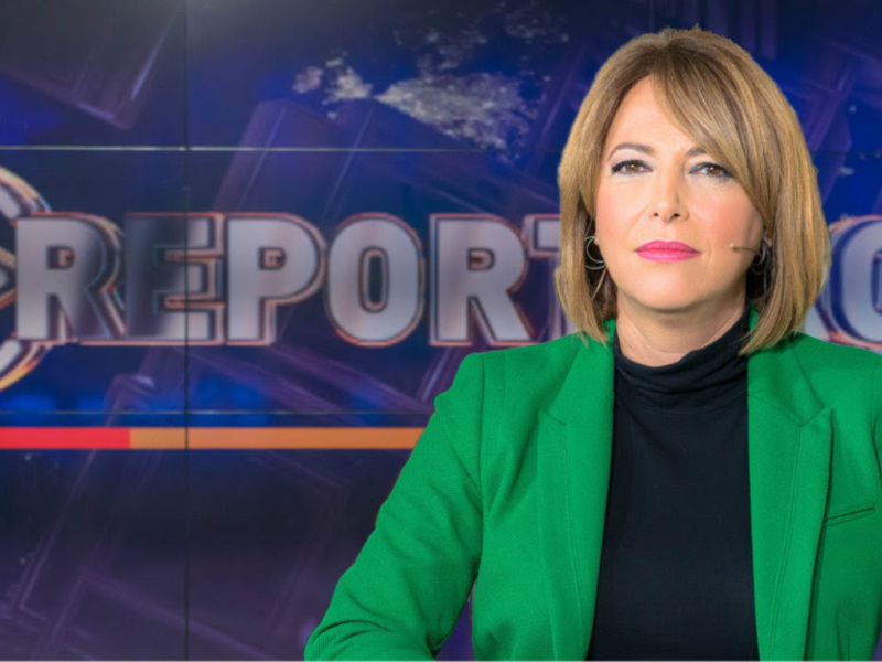 Reportera en estudio de noticias con fondo de pantalla de 'Los Reporteros'.