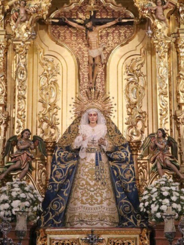 Retablo con la Virgen del Rocío y el Cristo crucificado, ornado con dorado y flores blancas.