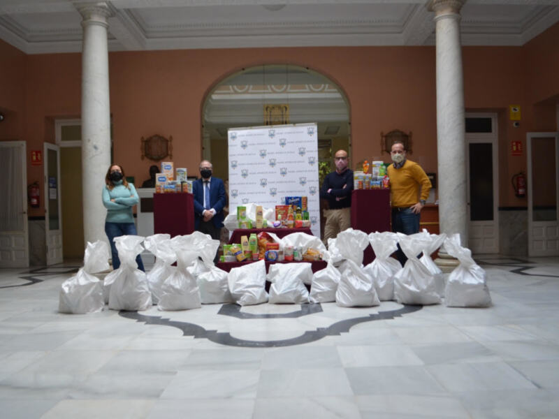 Voluntarios con donaciones de alimentos en un salón de estilo clásico.