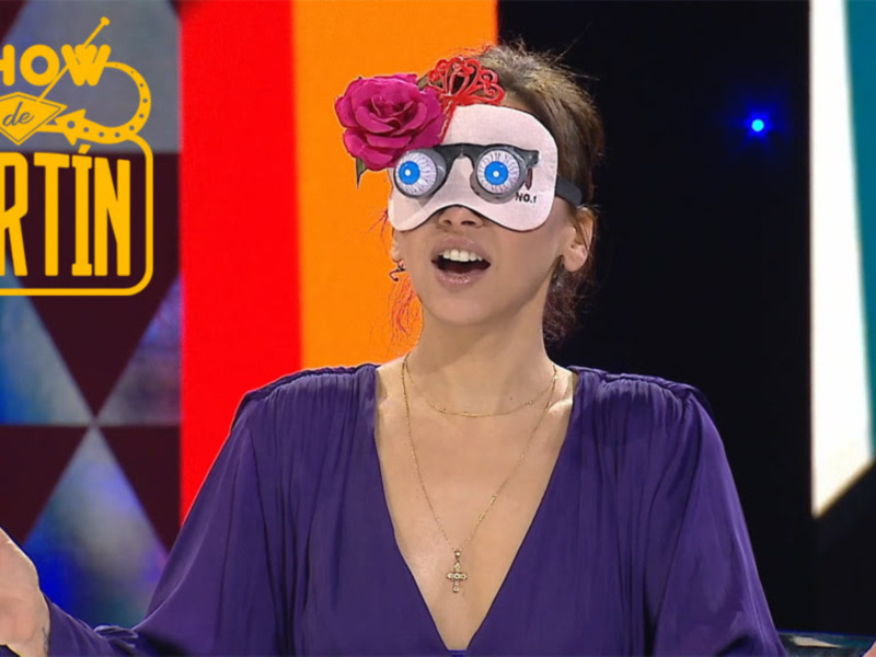 Participante en El Show de Bertín con máscara divertida y fondo colorido.
