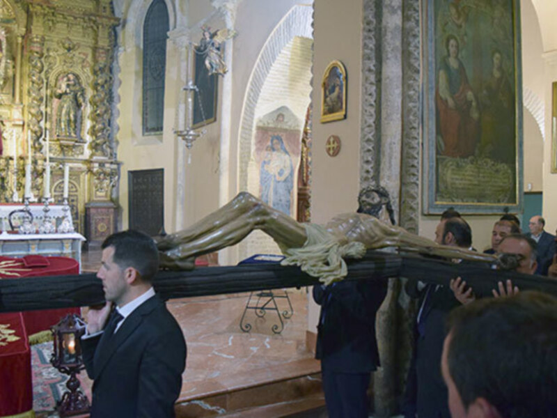 Funeral procession in a church, with mourners carrying a casket and an ornate statue.