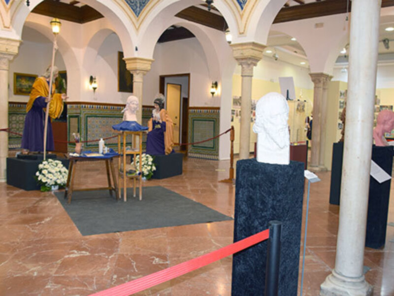 Interior de un museo con estatuas antiguas y bustos en un ambiente clásico con arcos y columnas.